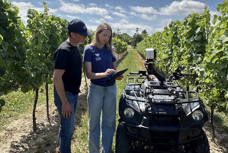 A Vivid Machines team member with the XV camera mounted on an ATV in a vineyard. Ottawa is investing up to C$1,693,412 to adapt the XV system from apple orchards to grape vineyards for early disease detection and yield prediction.